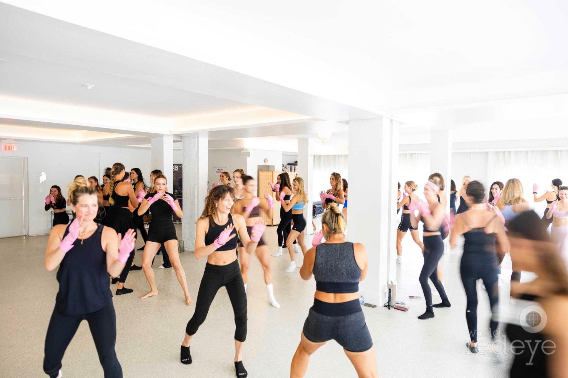 Attendees move together through a guided warm-up flow in the bright studio.