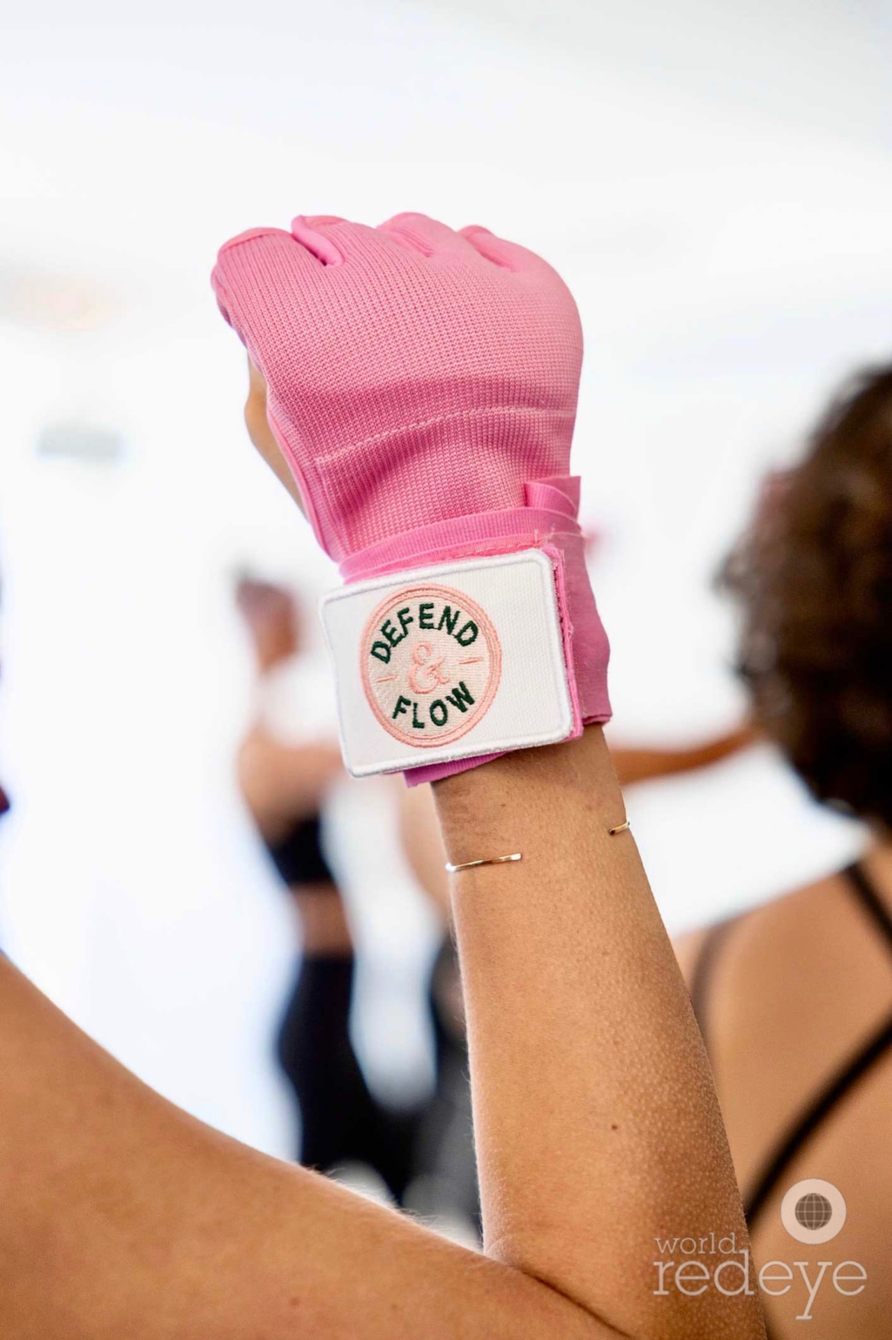 Close-up of a forearm and raised fist wrapped in pink, Defend & Flow logo visible.